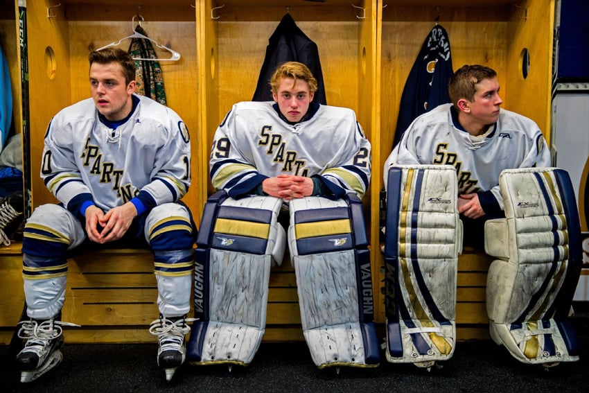 Photographer David Ellis' portrait of 3 high school hockey players in their team uniform in a locker room. Their jerseys says "SPARTANS."